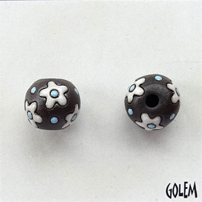 White flowers, blue dots on dark clay